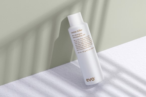 evo's water killer dry shampoo can leaning against a green backdrop
